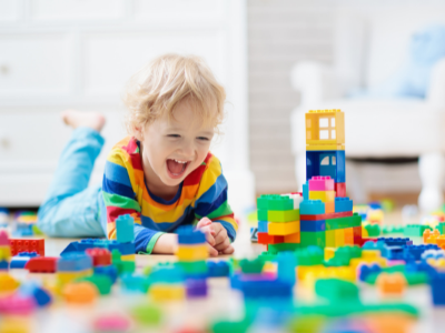 Small boy playing with blocks laying on floor