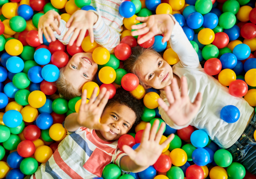 3 kids playing in a colorful ball pit