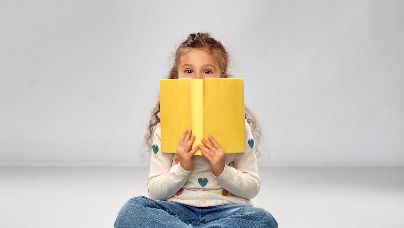 Child peaking over a book