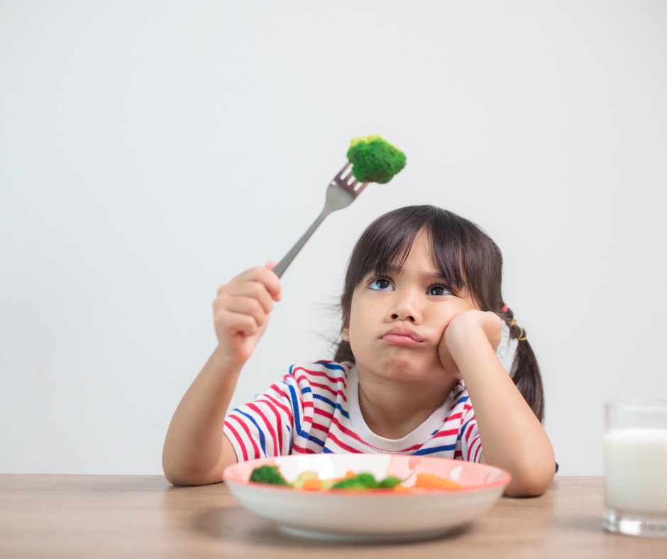 Child looking at broccoli with disgust
