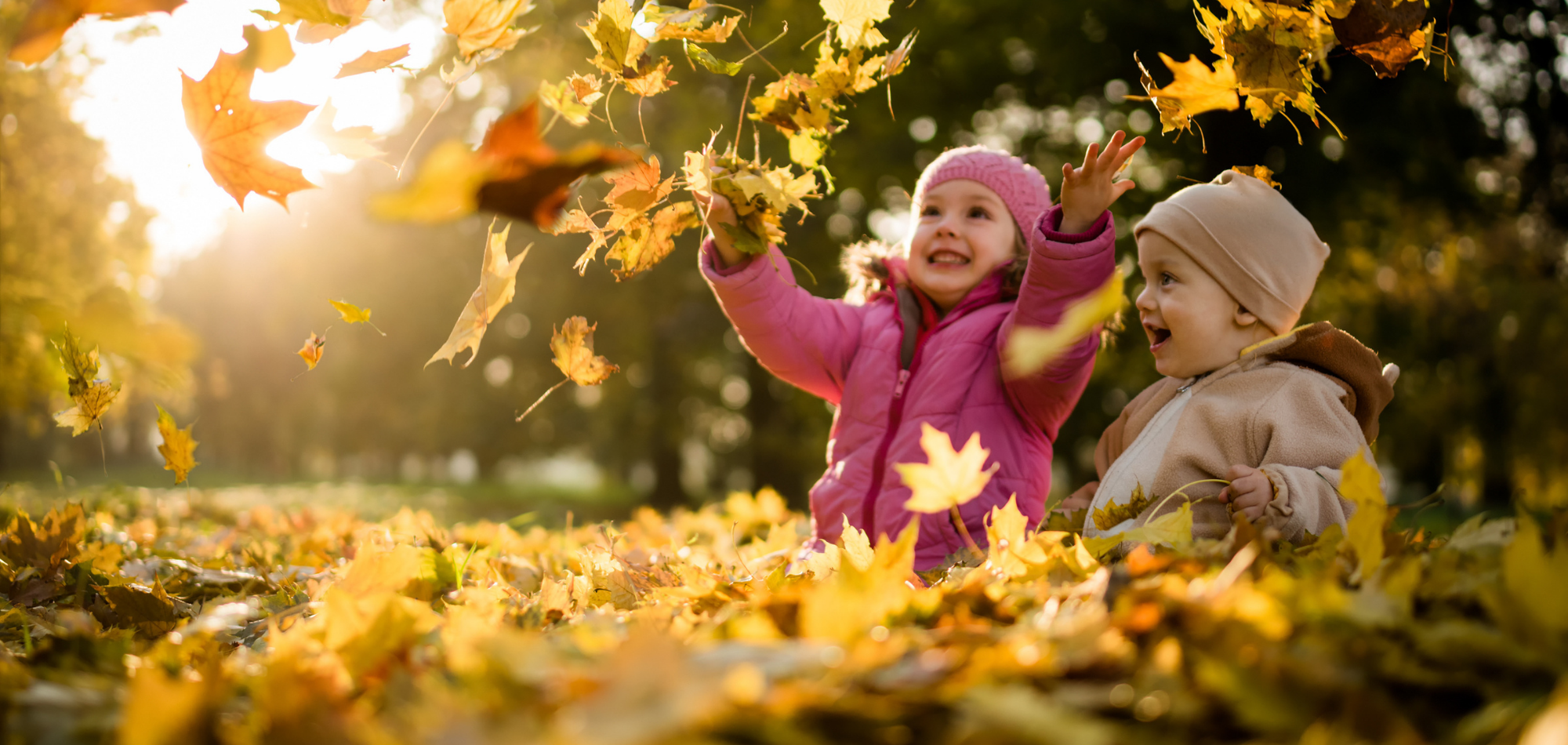 children playing in fall leaves
