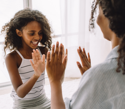 Mother and daughter playing pat-a-cake or other hands-on-hands song 