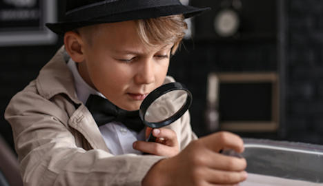 little boy dressed in detective outfit holding a magnifying glass, scavenger hunt concept